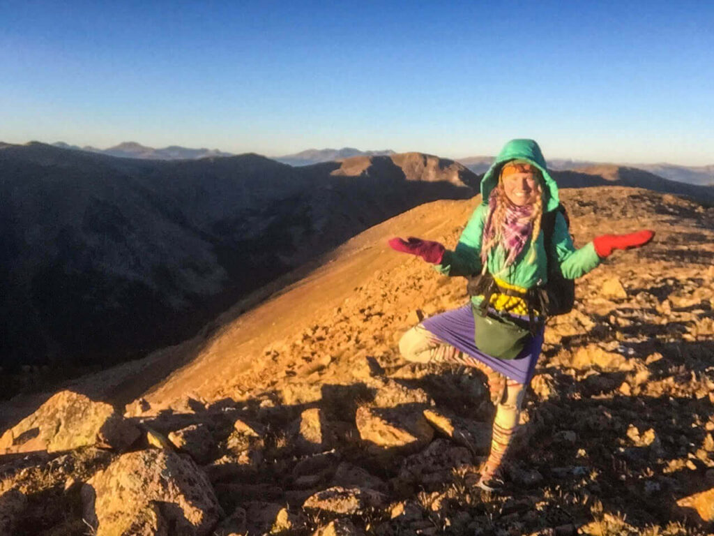 Woman backpacker on a ridge at sunrise in Colorado.