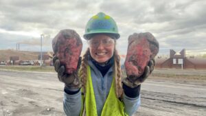 Woman working the sugar beet harvest with two red sugar beets the size of her head.