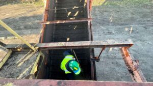 Man cleaning out the dirt return on a sugar beet piler.