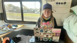 Woman with a laptop in a van blogging.