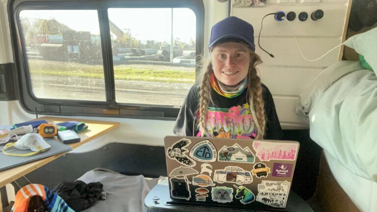 Woman with a laptop in a van blogging.