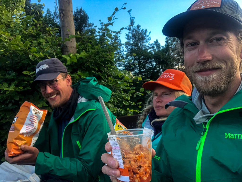 Three hikers eating a snack together.