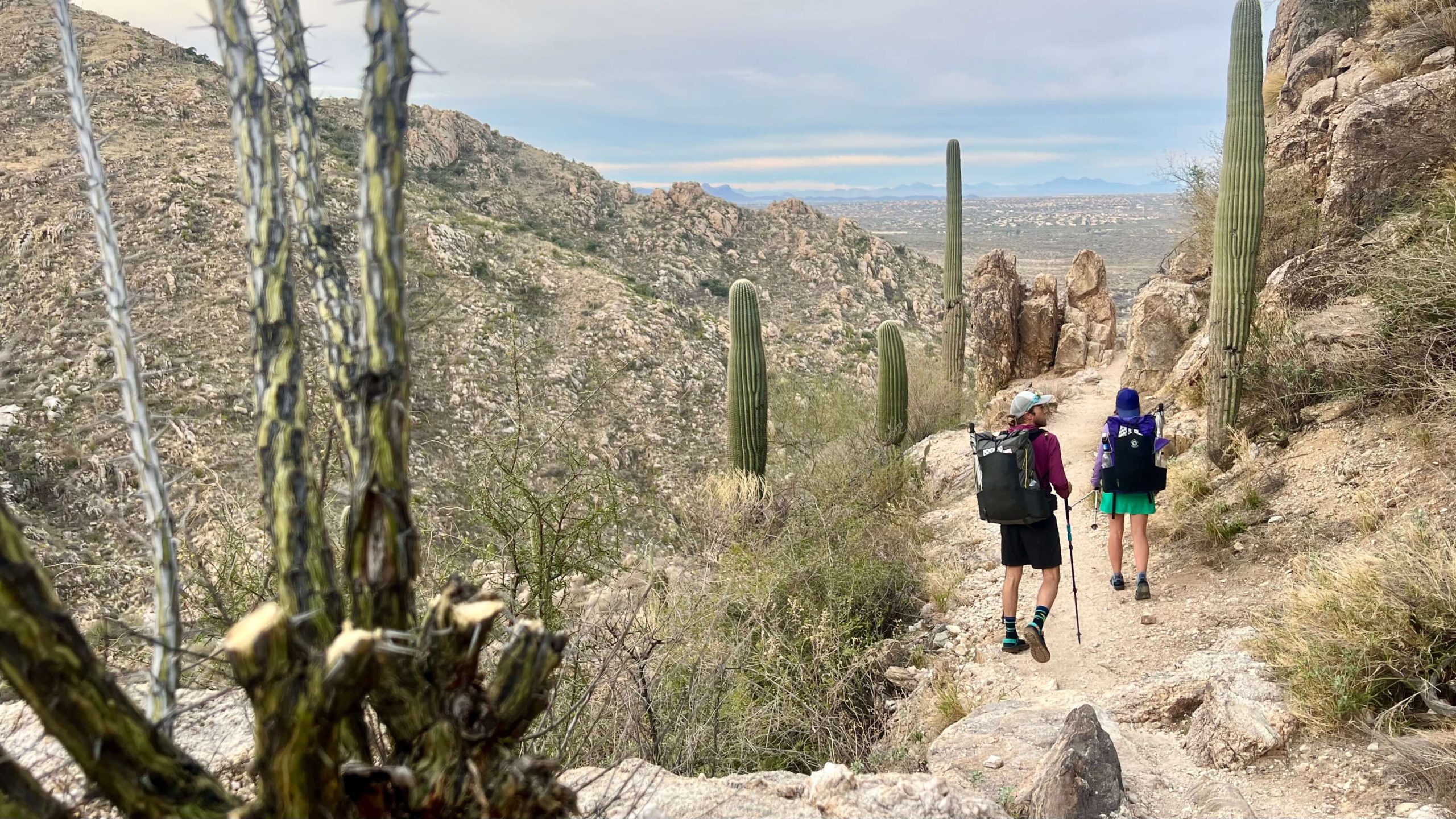 Two backpackers hiking downhill in Romero Canyon