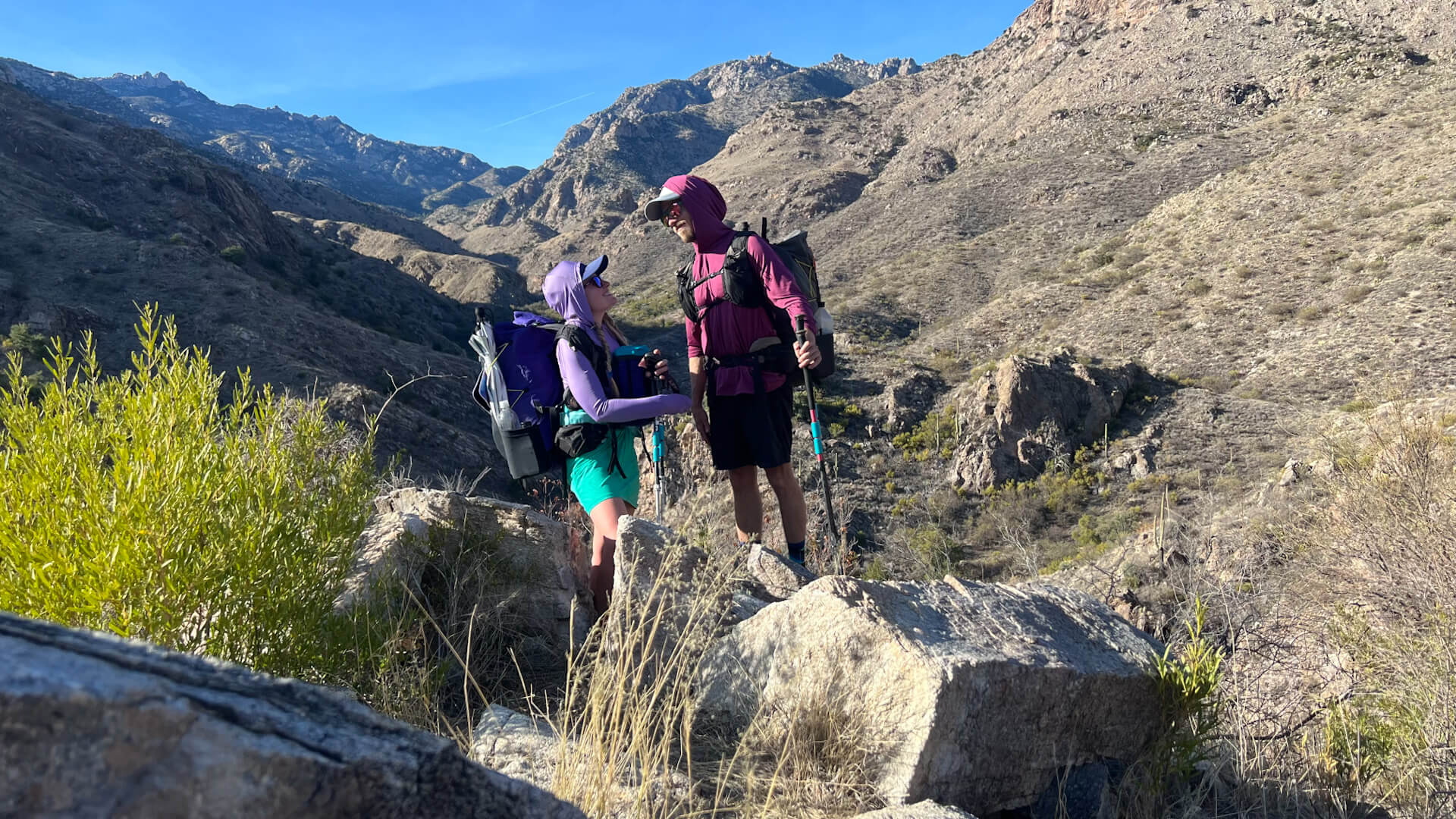 Two thru-hikers looking at each other with a desert view.