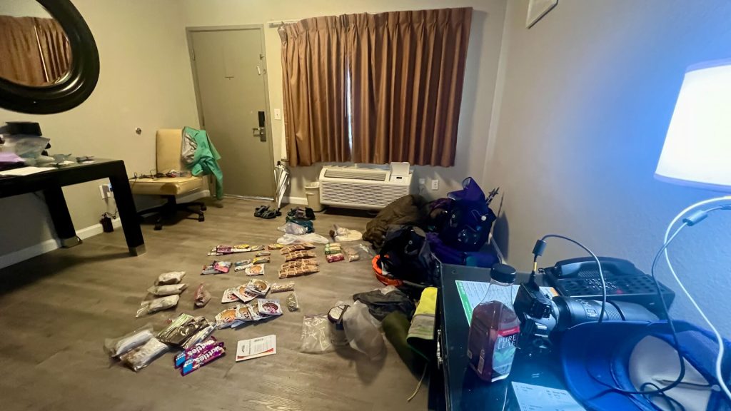 A hotel room with a thru-hiker's resupply across the floor.