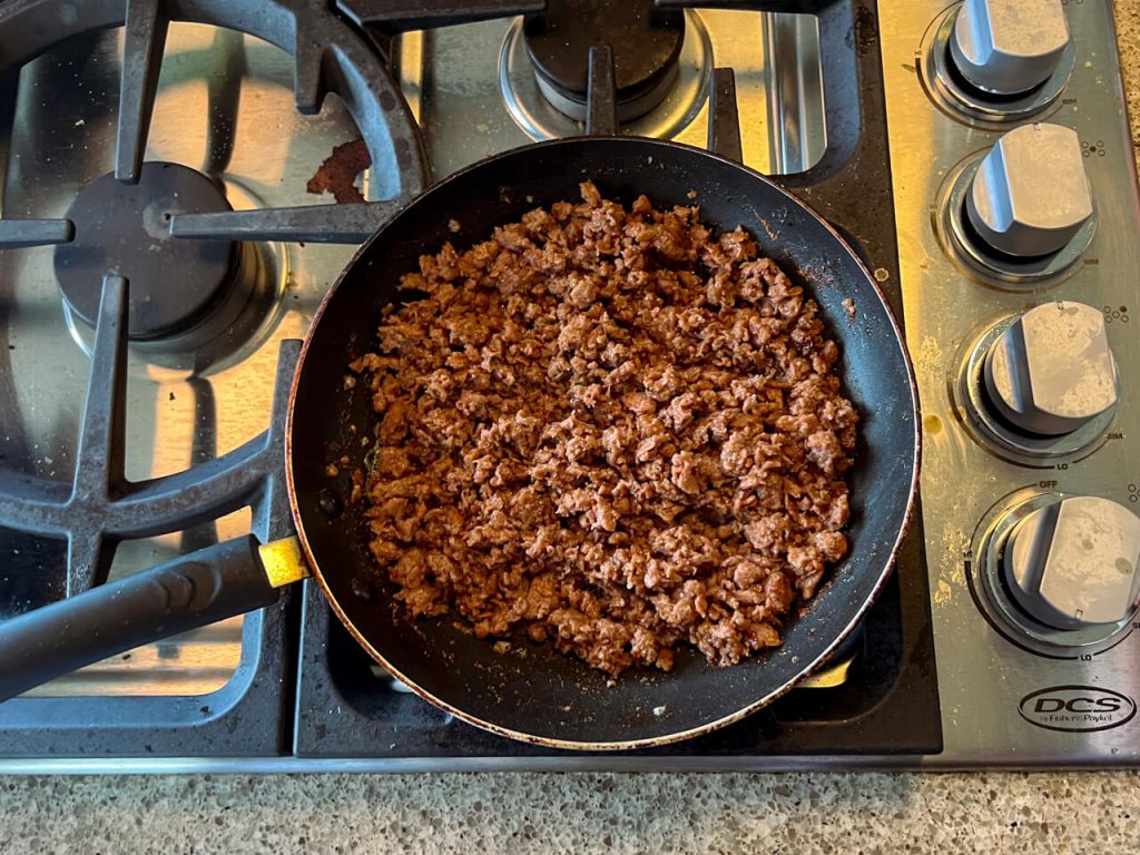 Beyond Beef frying in a skillet on the stove.