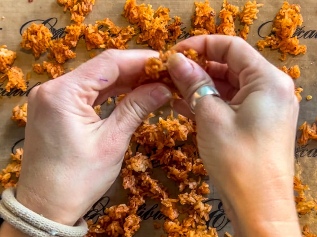 Breaking up clumps of dehydrating Spanish Rice halfway through the dehydration process.