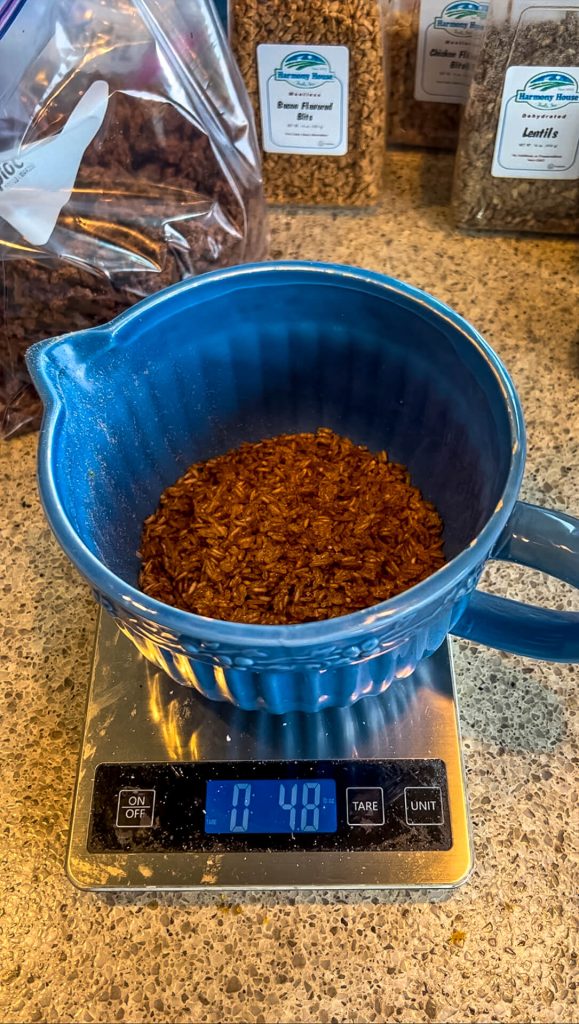 A bowl on a scale with dehydrated sesame ginger rice in it.