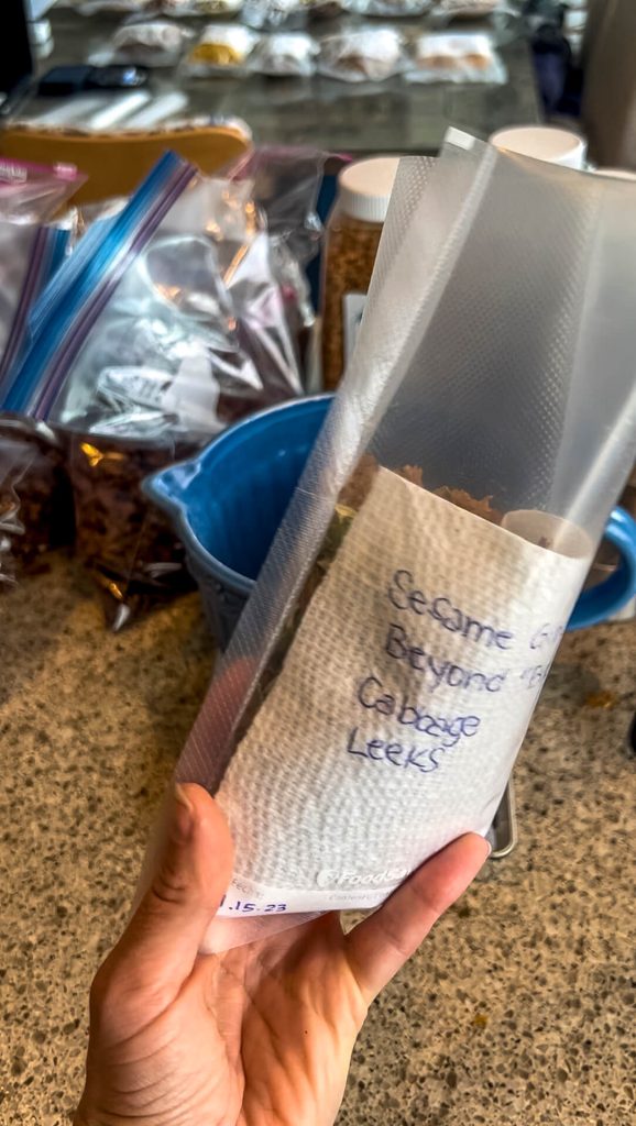 A woman holding a vacuum seal bag with dehydrated Chinese food and a paper towel recipe.