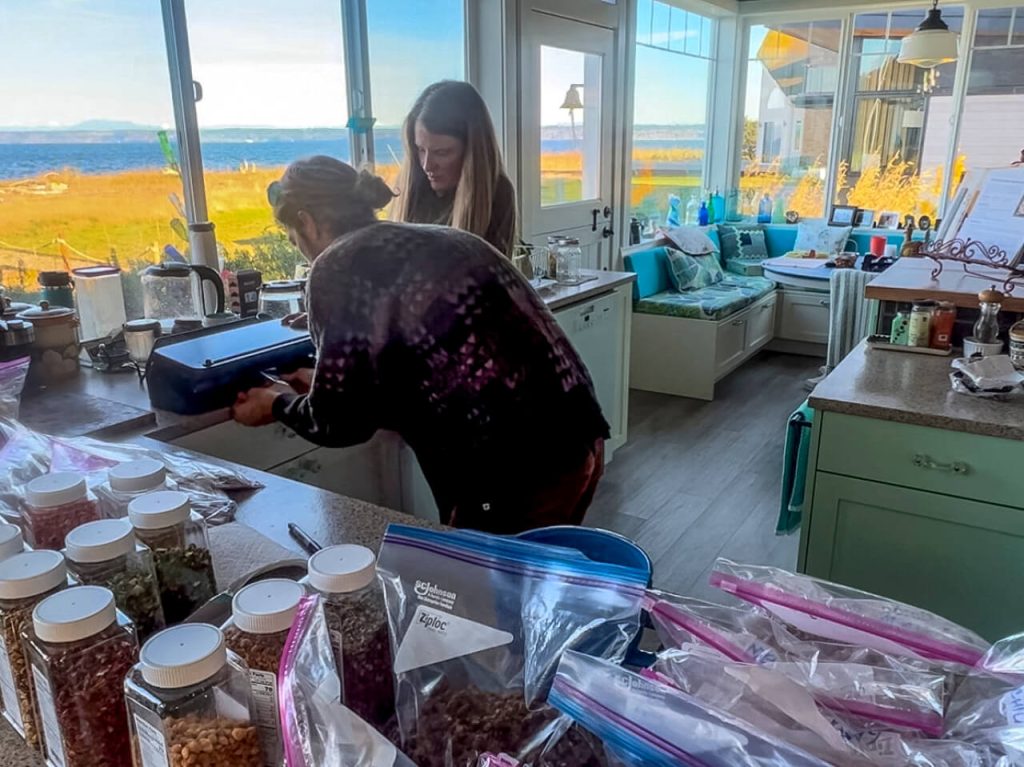 A couple vacuum sealing dehydrated Chinese Food backpacking meals in a kitchen.