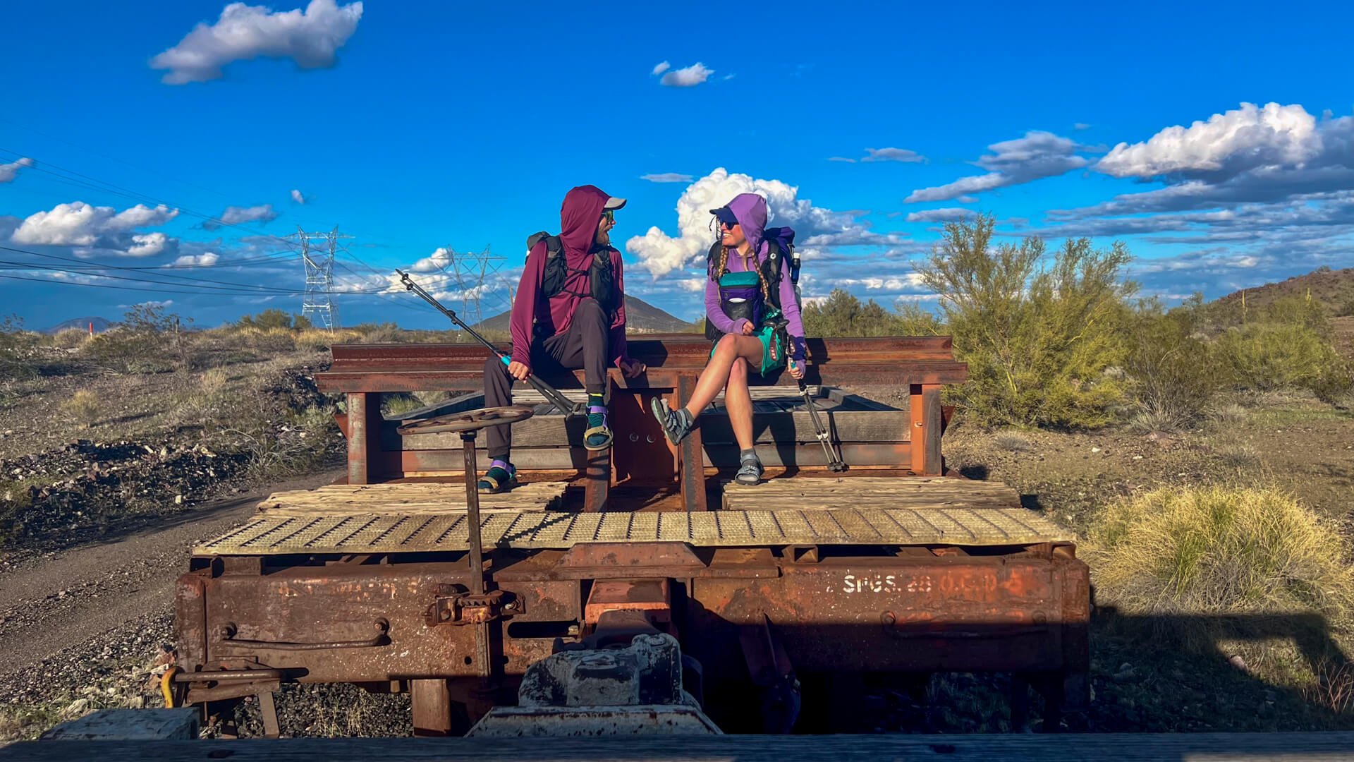 Two thru-hikers sitting on an abandoned trail car.
