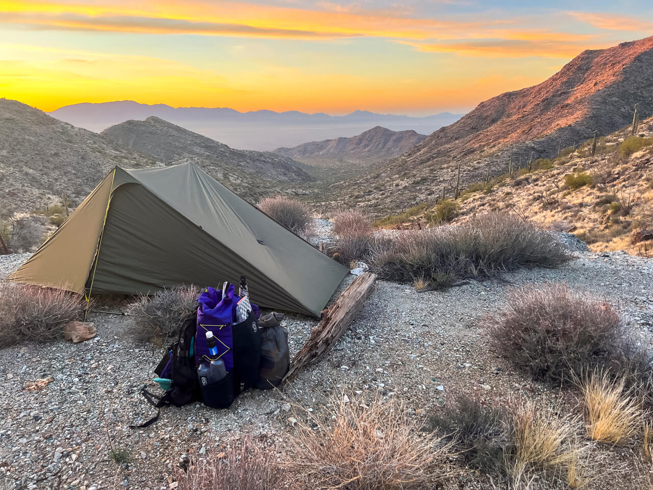 A tent and backpack set up at sunset in Arizona.