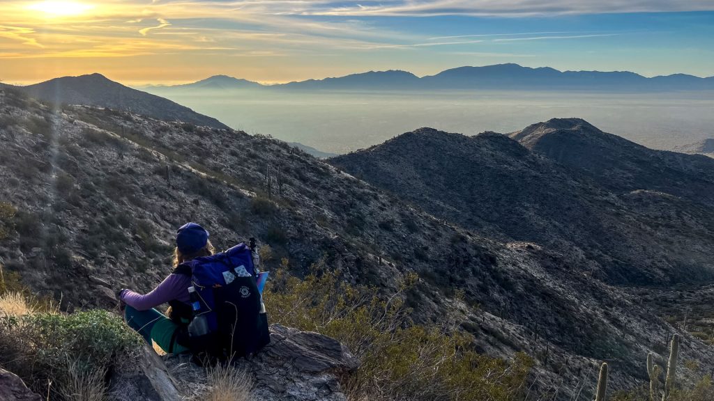 A woman backpacker taking a sit break part way up a climb.