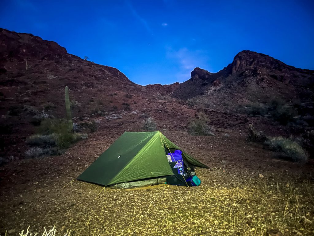 A tent and two backpacks set up at night.