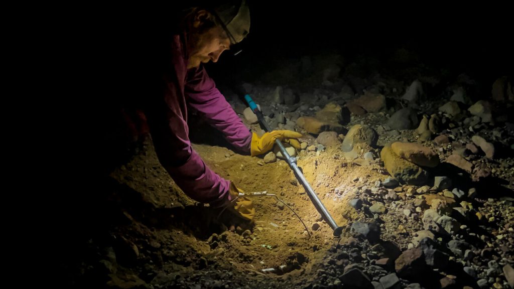 A hiker trying to dig up a food cache at night.