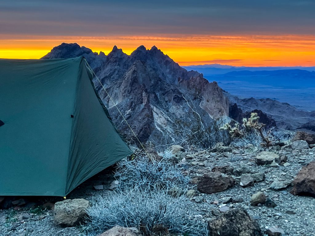 Sunset over mountains with a tent.
