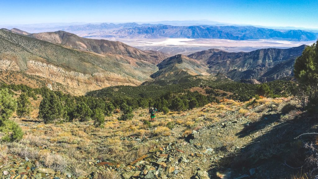 Woman backpacker cross-country hiking up a steep slope on the lowest to highest route.