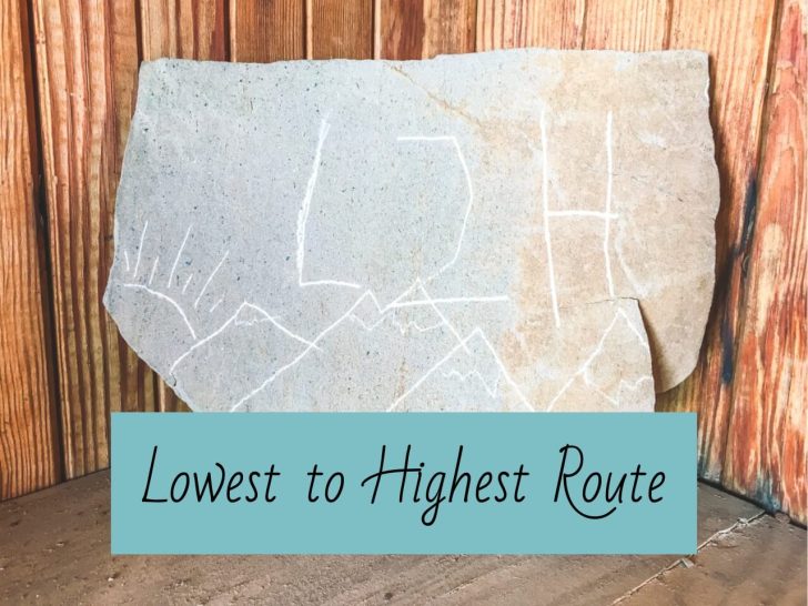 Stone sign with L2H scratched onto it with some mountains and a sun.