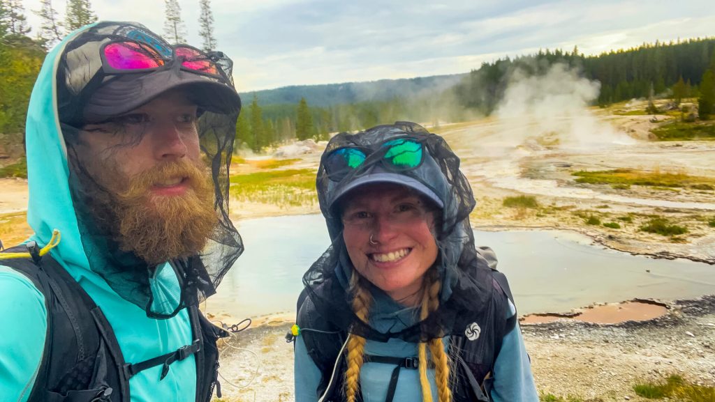 Two thru-hikers in Yellowstone on the CDT with bug head nets on.