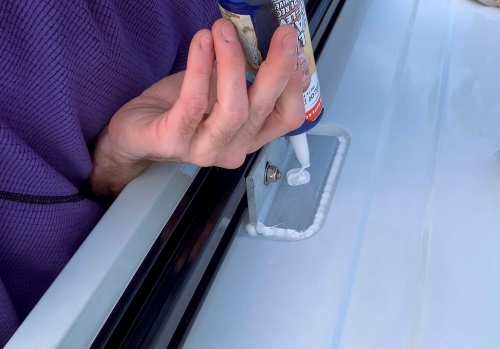 Adding lap sealant to the channel mounting brackets to waterproof the van roof.