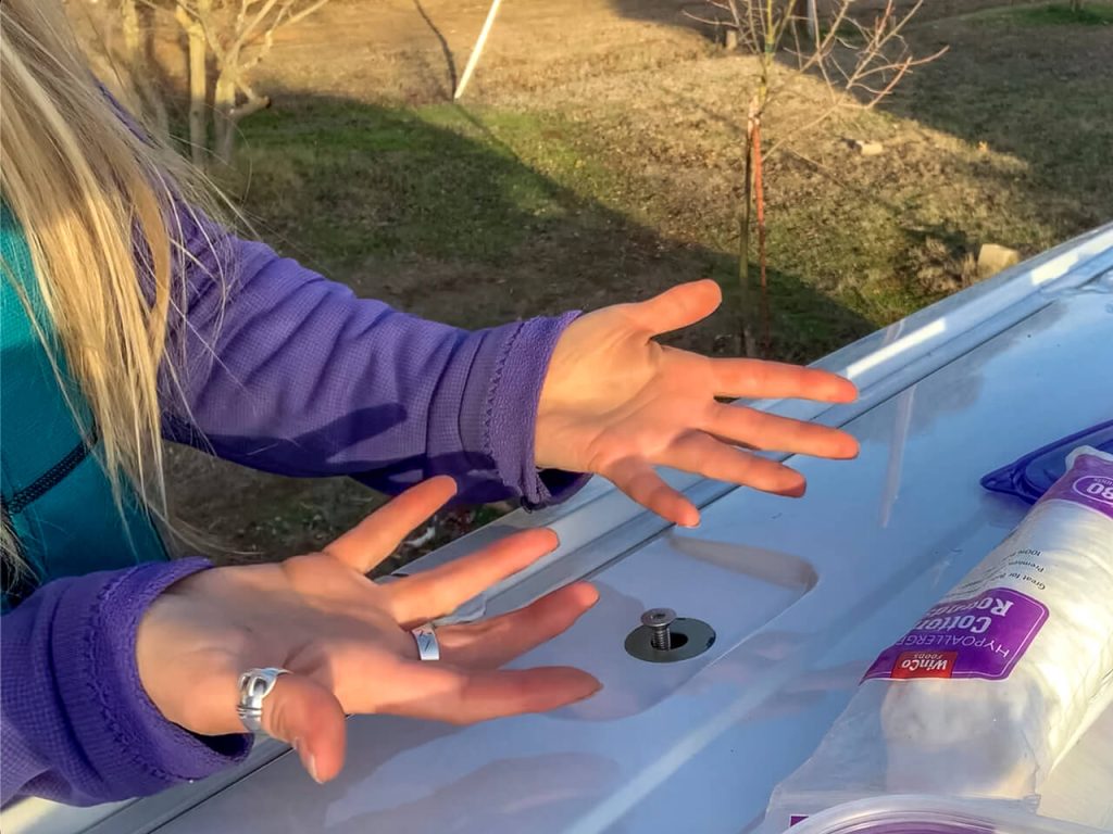 Woman showing how one of the roof rack bolt holes wasn't cut right in the factory.