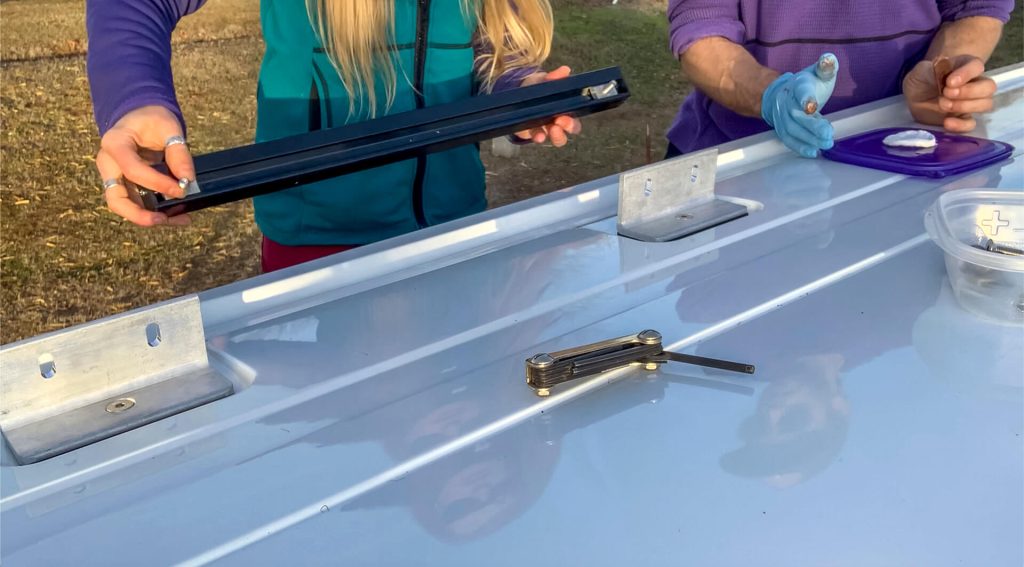 A van couple adding the channels to the channel mounting brackets on their roof rack.