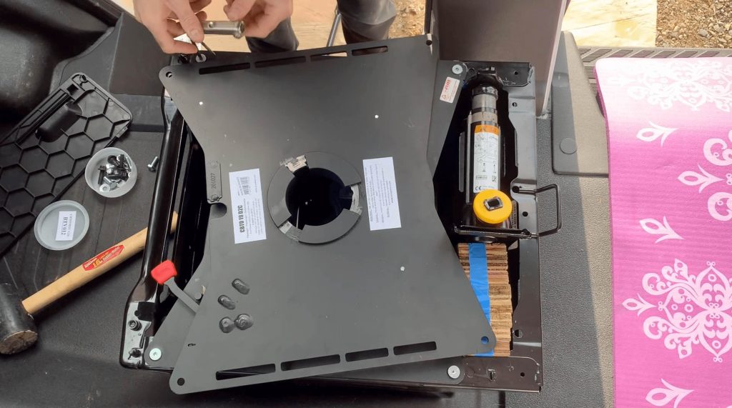 Adding and tightening bolts between the Scopema Swivel Seat and Ford Transit Seat Base with the help of a jack.