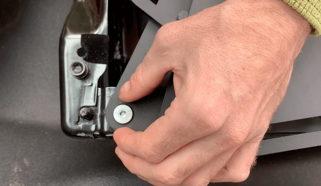 A man is hand screwing the Scopema Swivel Seat bolts into place.