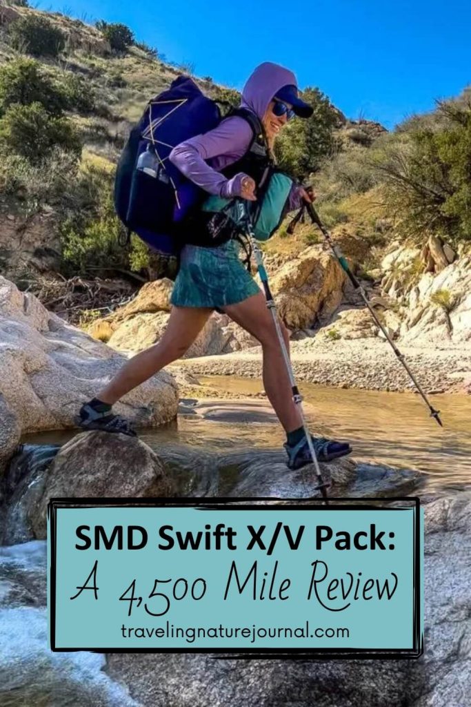 A woman crosses a creek with using an SMD Swift X backpack with text.