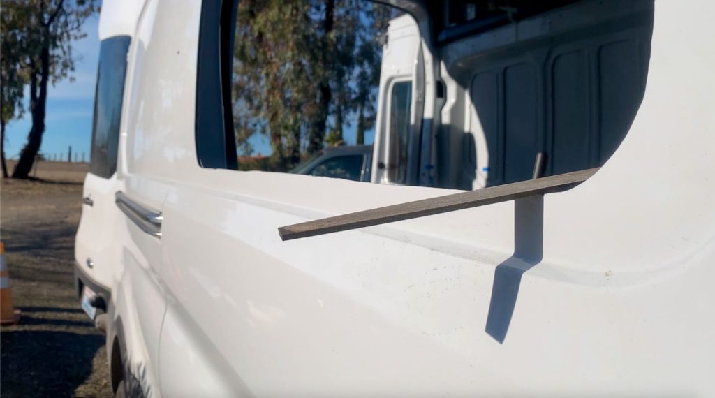 Using a metal file to smooth the edges of the van sliding window hole in the door.