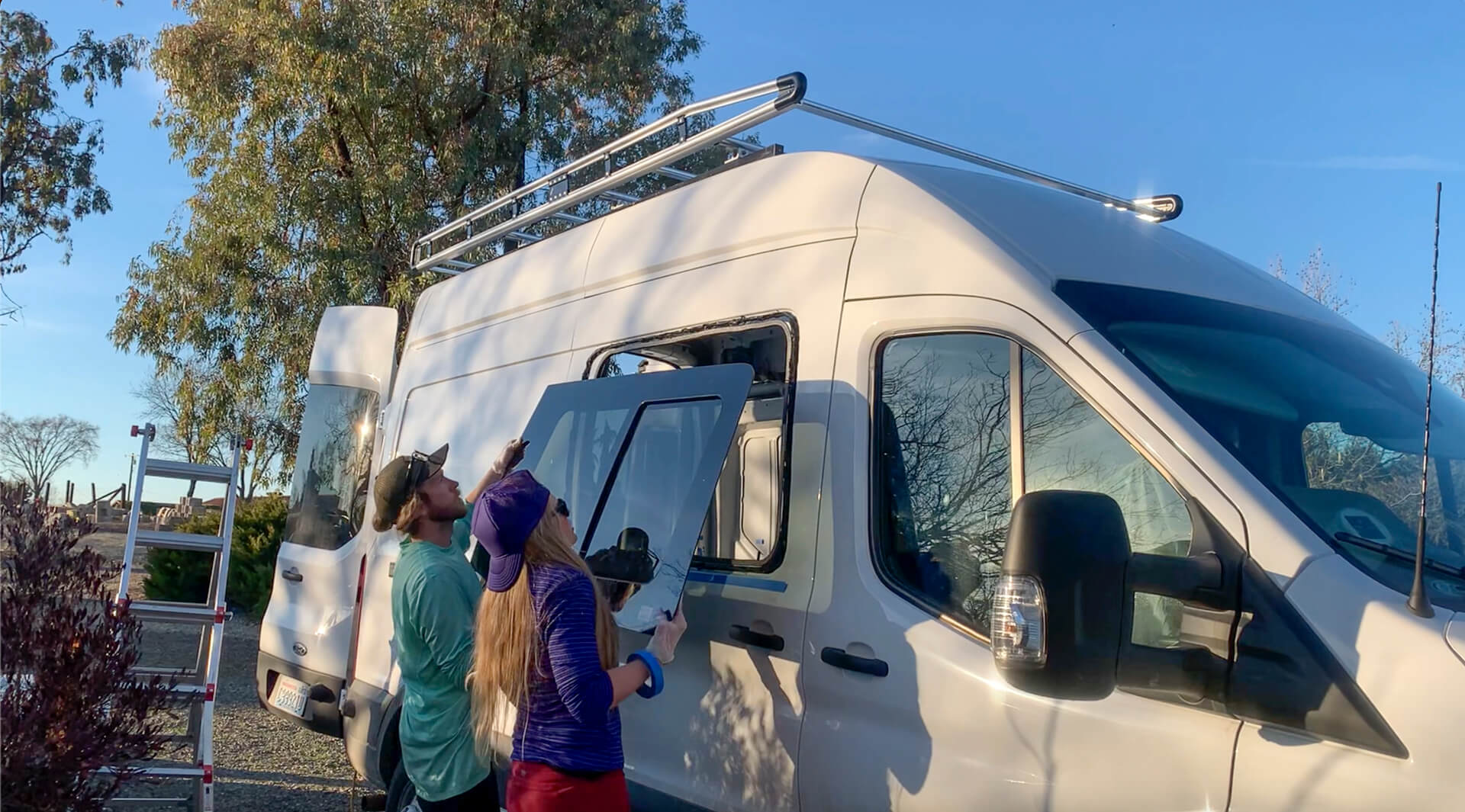A van couple placing a sliding window onto their Ford Transit DIY van build.
