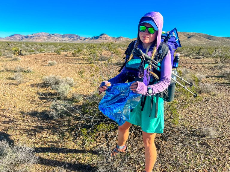An upset hiker picking up balloon trash in the desert.