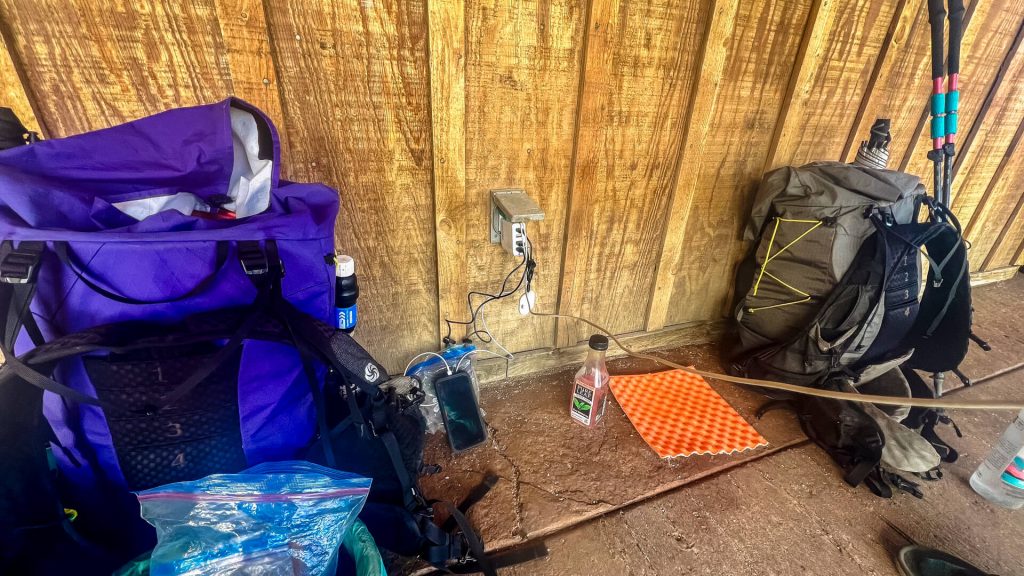 Two backpacking packs against a wall and electronics charging.