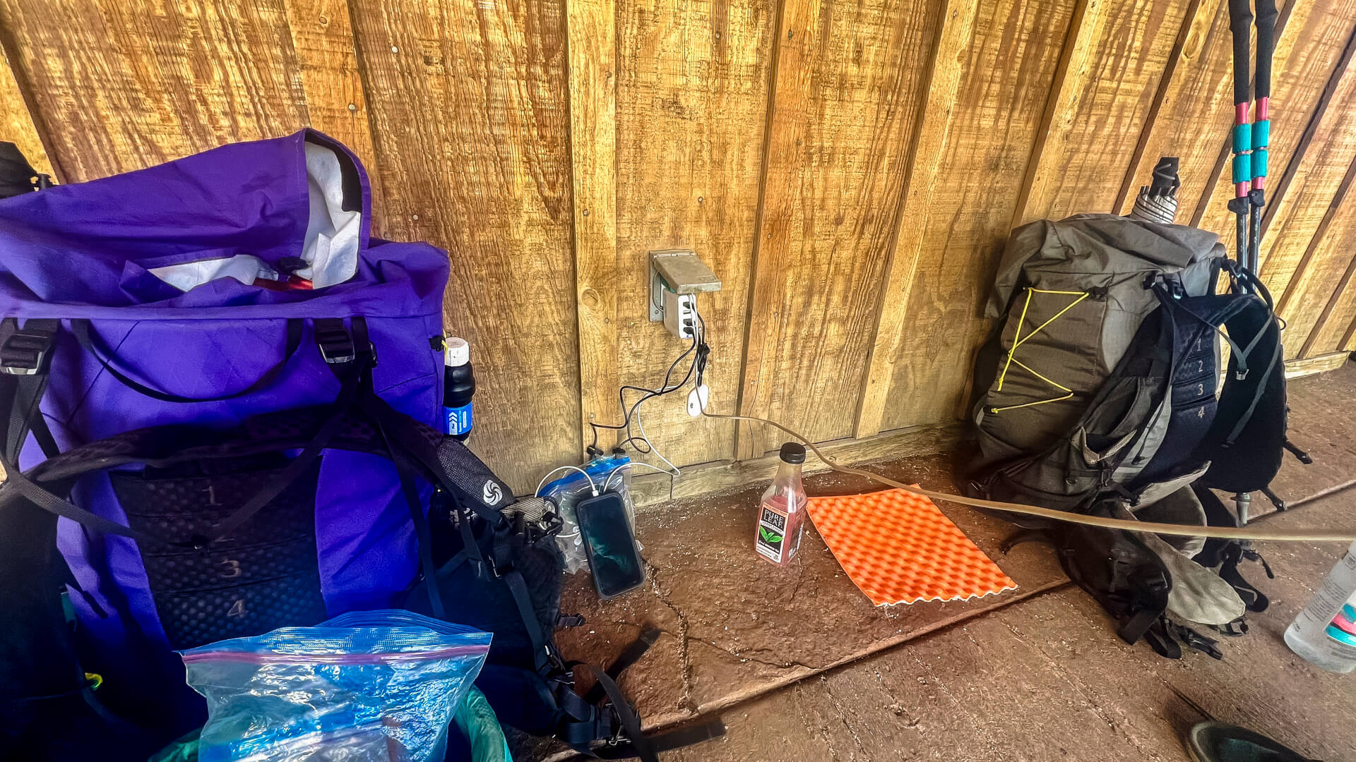 Two backpacking packs against a wall and electronics charging.