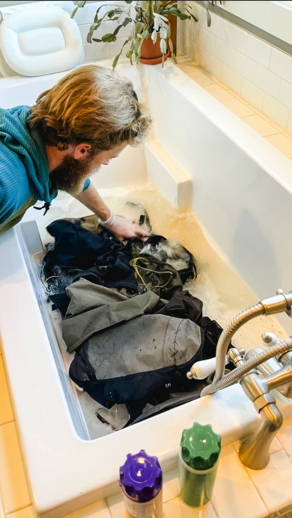 Thru-hiker putting backpacks in a tub to clean them.