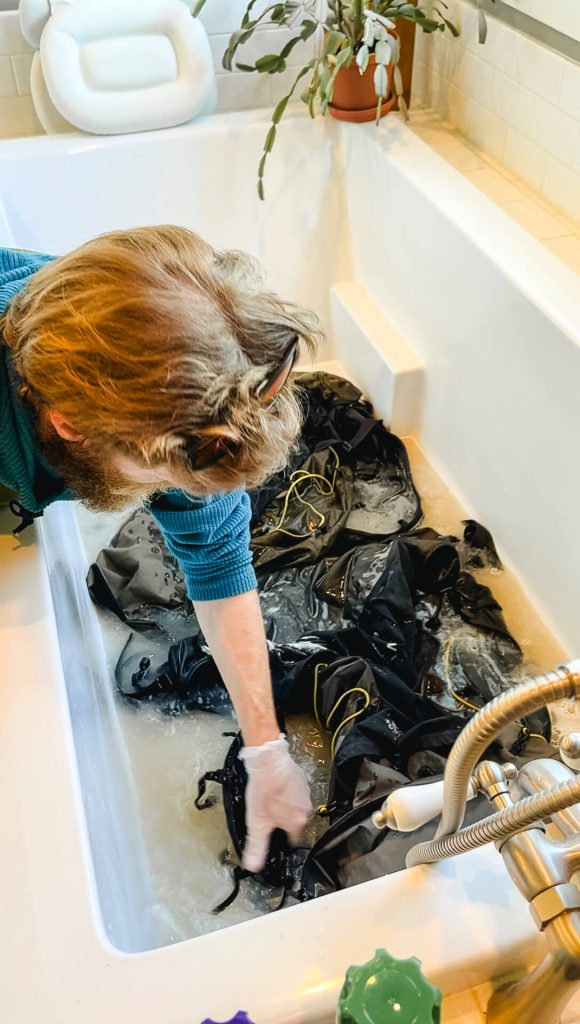 Thru-hiker washing a hiking backpack in a tub.