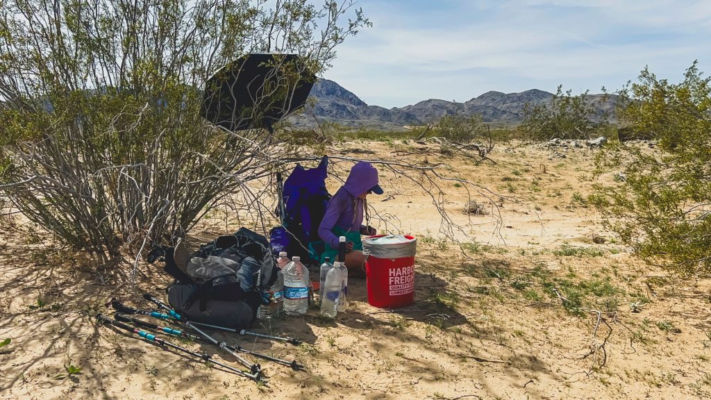 Sorting our cache with the shade of an umbrella stuck in a creosote bush.