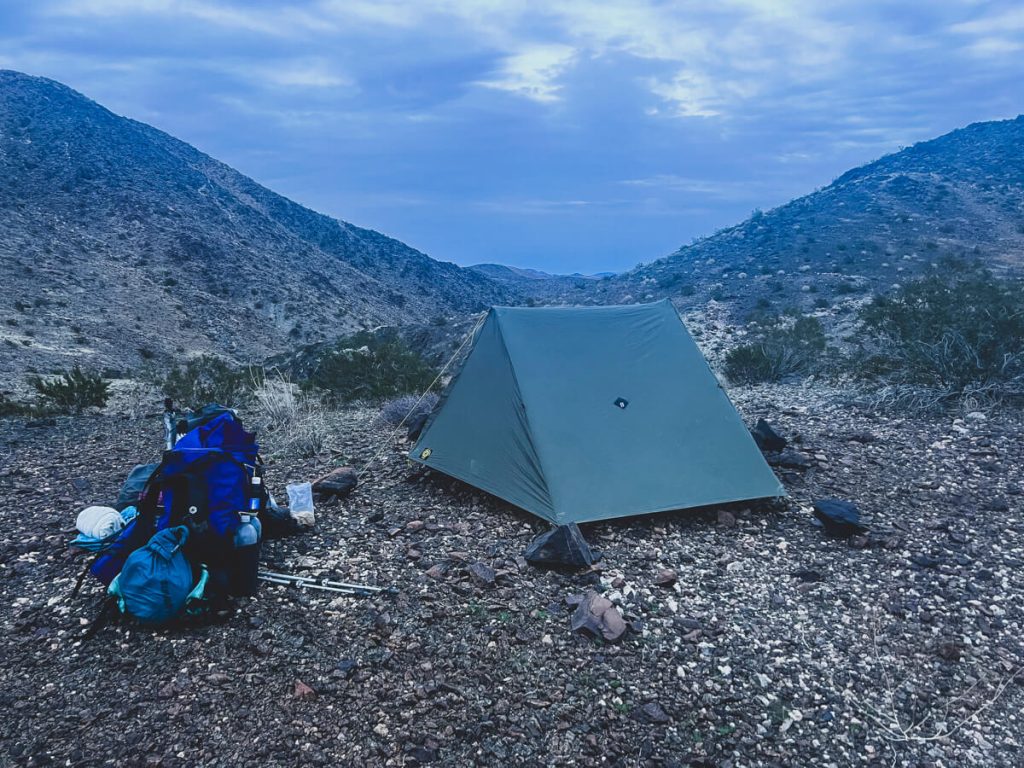 Desert campsite in California with backpacks next to the tent.