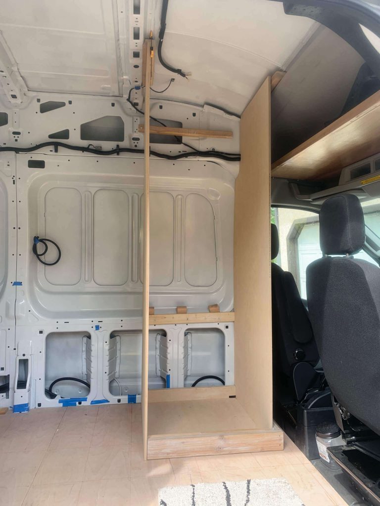 Securing the indoor van shower walls to the van's ceiling.