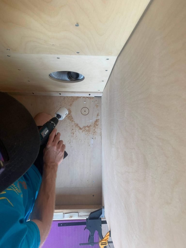 Drilling the van shower drain hole through the van floor,