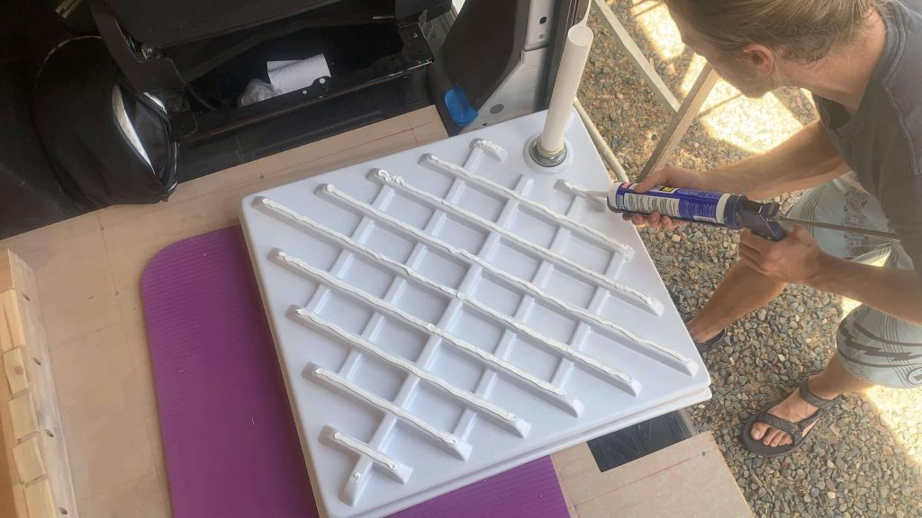 Adding loctite marine adhesive to the bottom of the shower pan to glue it to the floor.