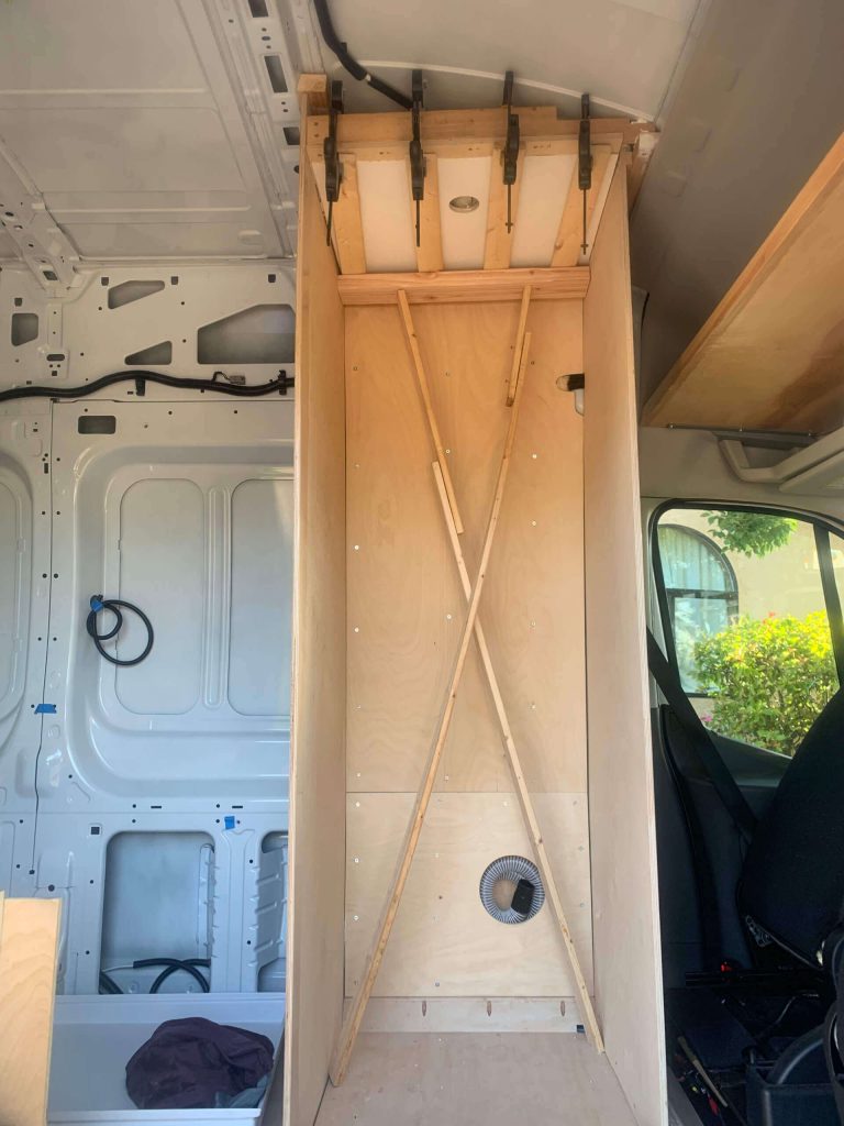 Holding pressure on the FRP board to glue the van shower ceiling on.