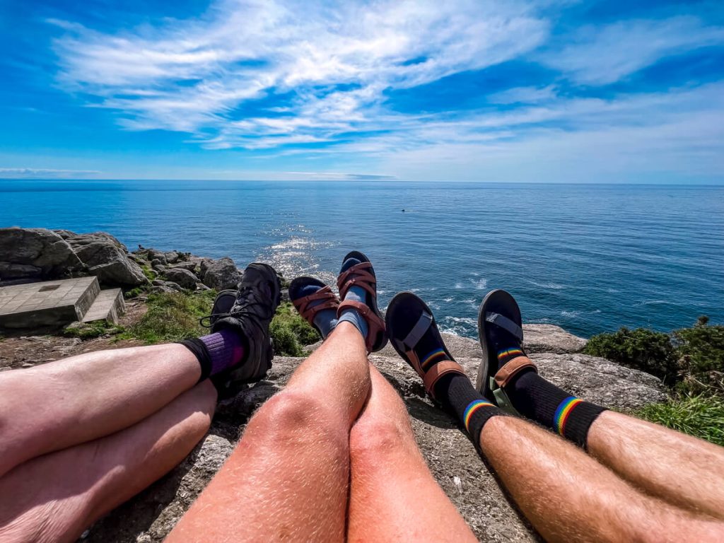 Three pairs of feet extended on a rock each with their preferred hiking footwear.