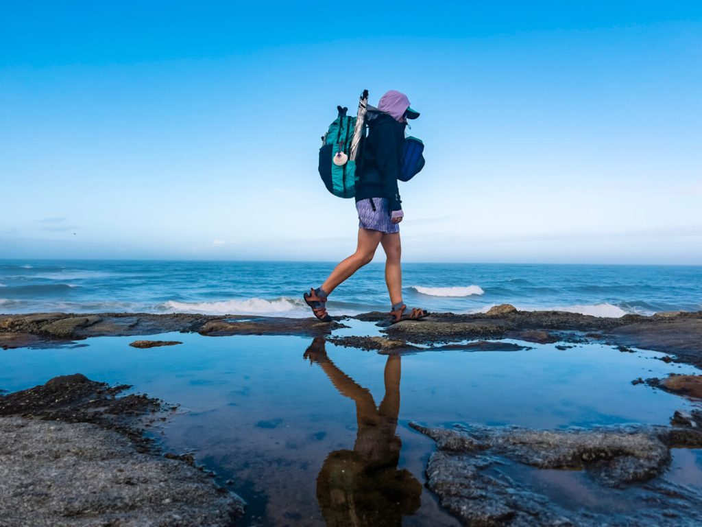 Veggie walks along some rocks by the coast on the Portuguese Camino.