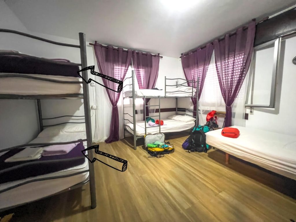 Arrows pointing to a provided blanket at the base of a bunk bed on the Camino de Santiago.