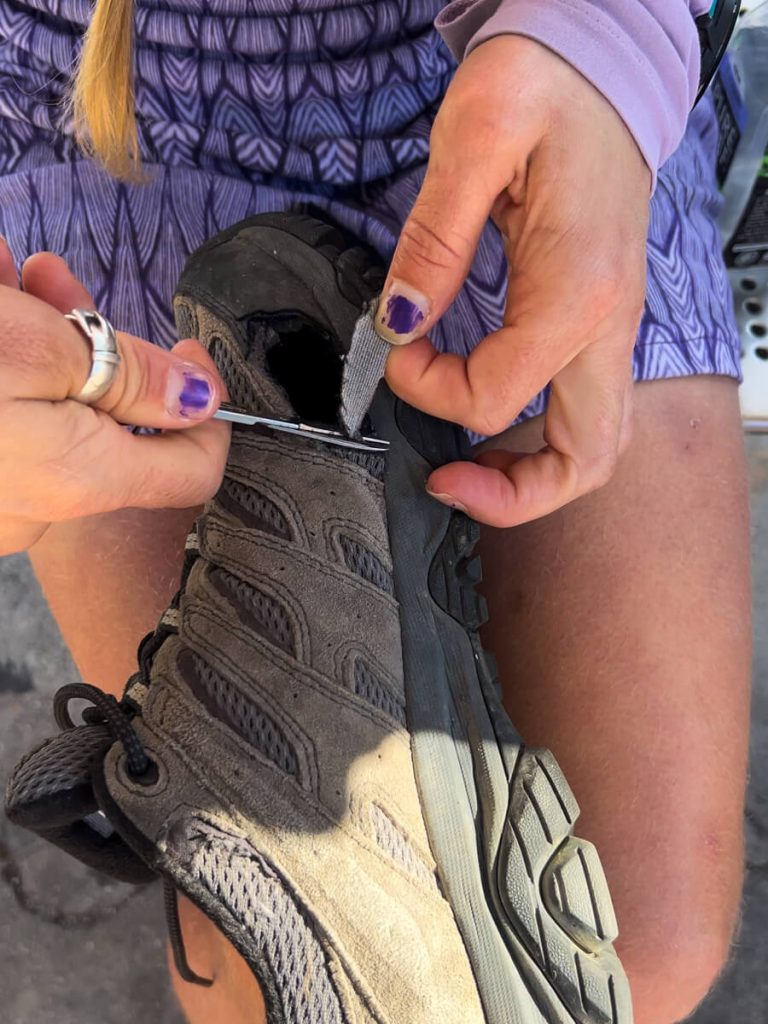 Me cutting a hole in my Mom's trail runner so her bunion can prevent hiking blisters.
