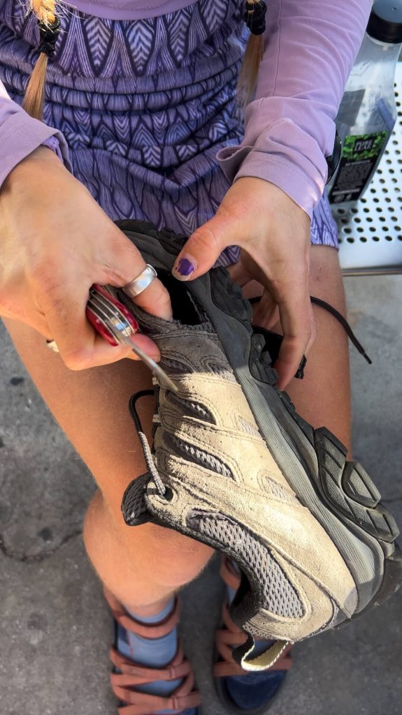 Me cutting a hole in my Mom's trail runner so her bunion can prevent hiking blisters.