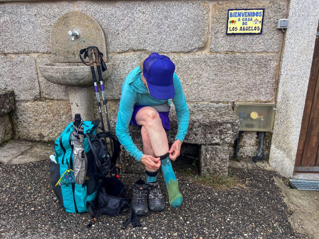 Woman changing her socks mid-way through the day to avoid blisters while hiking on the Portuguese Camino