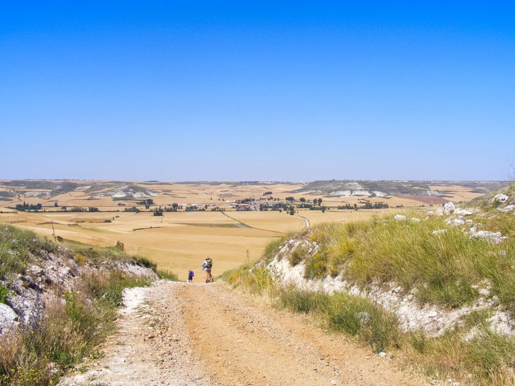 Two pilgrims ahead on the Camino where there is very little shade.