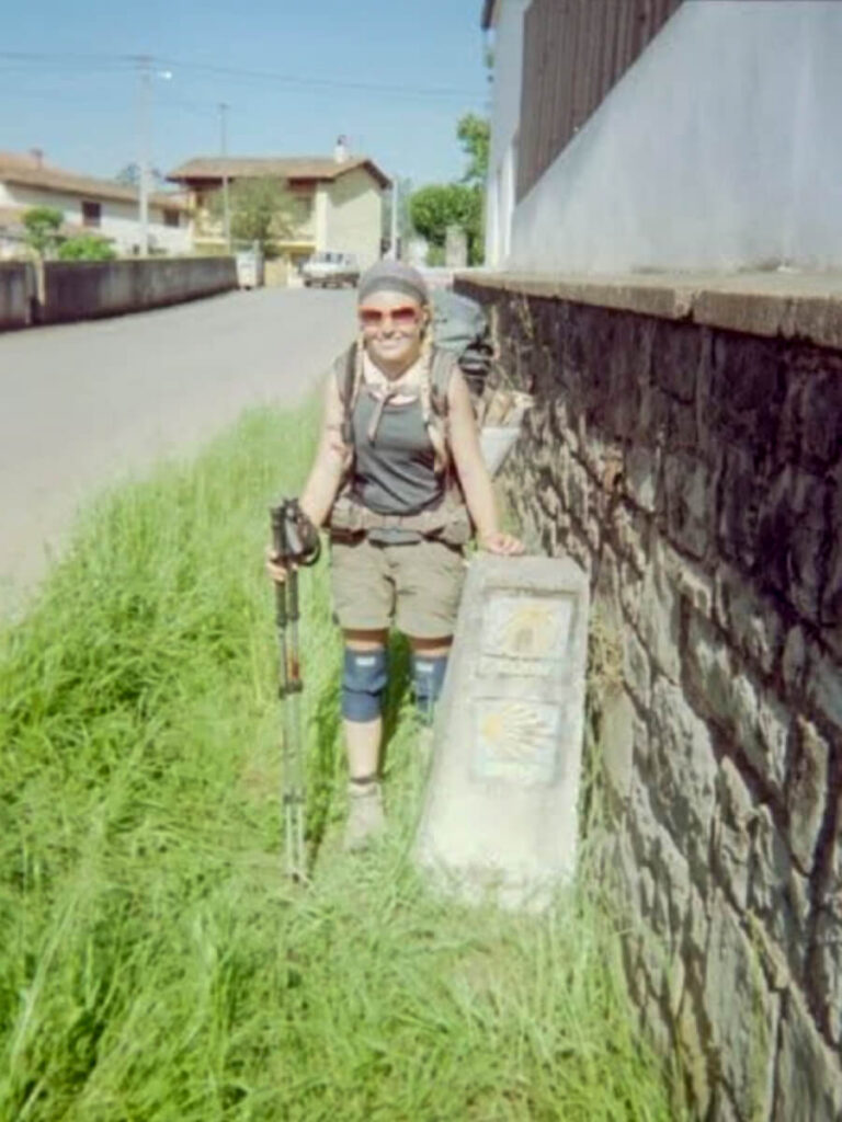 A hiker with a stone Camino marker.